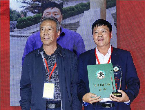 中華木工委專(zhuān)家委員會(huì )專(zhuān)家李永革（左）為楊俊平（右）頒授“中華木作大師”榮譽(yù)